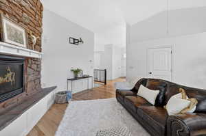 Living room with lofted ceiling, light wood-style flooring, and a fireplace