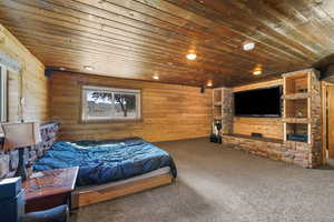 Carpeted bedroom with wood ceiling, wooden walls, and recessed lighting
