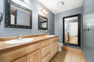 Bathroom with light tile patterned floors and double vanity