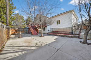 Rear view of property with a fenced backyard, stairs, and a patio area