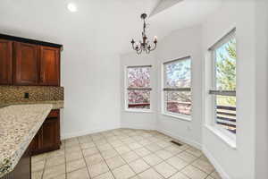 Unfurnished dining area with light tile patterned flooring, a chandelier, lofted ceiling, and recessed lighting