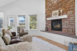 Living area featuring a fireplace, light wood-style floors, and high vaulted ceiling