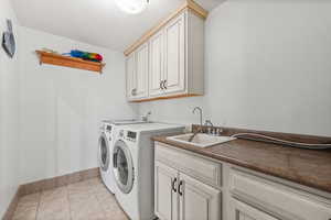 Washroom with light tile patterned floors, independent washer and dryer, and cabinet space