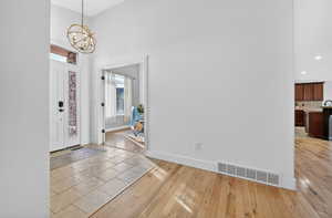 Foyer entrance with light wood-style flooring, a high ceiling, a chandelier, and recessed lighting