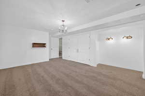 Unfurnished bedroom featuring carpet floors, a closet, a chandelier, and a textured ceiling