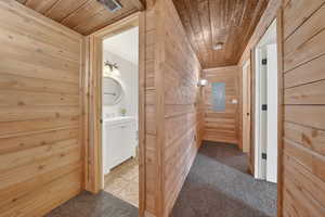 Corridor with wooden walls, carpet floors, wooden ceiling, and electric panel