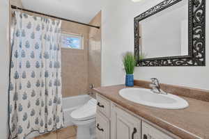 Full bath with shower / bath combo, vanity, and light tile floors