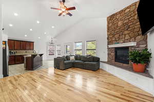 Living room featuring high vaulted ceiling, a chandelier, light wood finished floors, recessed lighting, and a stone gas fireplace