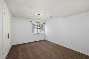 Spare room featuring dark carpet and a textured ceiling
