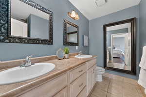 Ensuite bathroom featuring double vanity, light tile  floors, and a textured ceiling