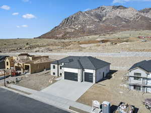 View of front of property featuring a mountain view, concrete driveway, a pergola, stone siding, and a shingled roof