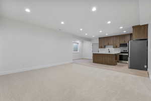 Kitchen featuring open floor plan, appliances with stainless steel finishes, recessed lighting, light countertops, and a kitchen island