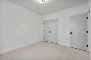 Unfurnished bedroom with carpet floors, a closet, and a textured ceiling