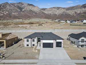 View of front of house featuring a mountain view, driveway, stone siding, and a garage