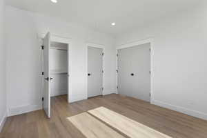 Unfurnished bedroom with light wood-style flooring, recessed lighting, and two closets