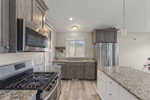Kitchen with stainless steel appliances, hanging light fixtures, LVP flooring and large granite island.