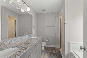 Full bathroom featuring a bath, light wood finished floors, double vanity, and a stall shower