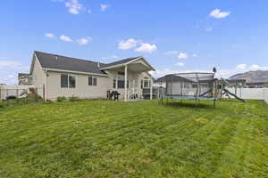 Back of property with a playground, a fenced backyard, stucco siding, a trampoline, and roof with shingles