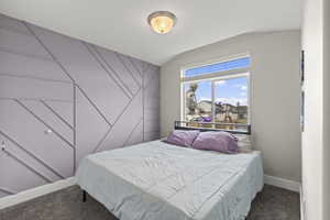 Carpeted bedroom with baseboards and an accent wall