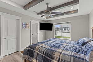 Bedroom with beam ceiling, light wood-style floors, access to exterior, and a ceiling fan