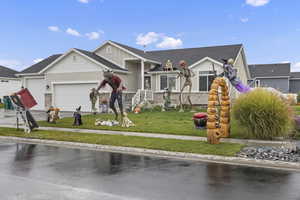 View of front facade featuring a front yard, a garage, driveway, and stone siding