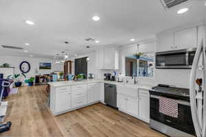 Kitchen with stainless steel appliances, white cabinetry, a peninsula, decorative backsplash, and recessed lighting