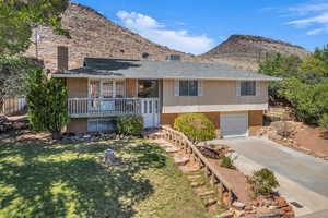 View of front of house featuring a chimney, driveway, brick siding, and a mountain view