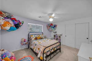 Bedroom with light colored carpet, ceiling fan, and a closet