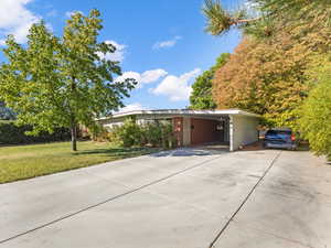 View of front facade with newly installed concrete driveway, brick siding, and an attached carport