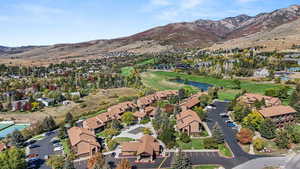 Aerial view of property's location with nearby suburban area, a water and mountain view, and a golf club