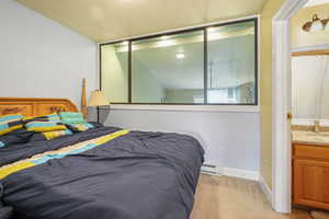 Bedroom with light colored carpet, a baseboard radiator, and a textured ceiling