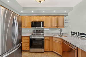 Kitchen featuring stainless steel appliances, light stone countertops, recessed lighting, a textured ceiling, and light tile patterned flooring