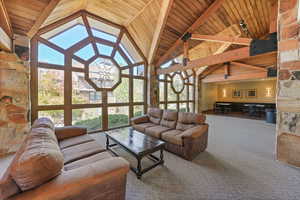 Common area with carpet, a wood ceiling with exposed beams, and high vaulted ceiling