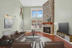 Living room featuring a fireplace, wood finished floors, and a high ceiling