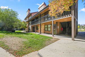 View of unit with a lawn, stone siding, stairs, and a chimney