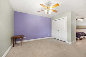 Unfurnished bedroom with light carpet, ceiling fan, and a closet