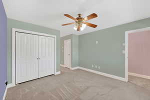 Unfurnished bedroom with light carpet, ceiling fan, and a closet