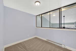 Empty room with a baseboard radiator, carpet, and a textured ceiling