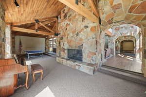 Common area with outdoor stone fireplace, carpet, high vaulted ceiling, and a wood ceiling with exposed beams