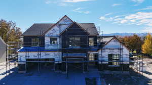 Back of property with a shingled roof, a mountain view, and stairs