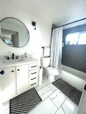 Bathroom with vanity, shower / bath combo with shower curtain, and light marble finish flooring