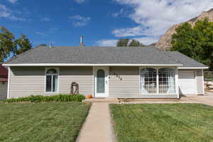 Ranch-style house with roof with shingles, a front yard, and an attached garage