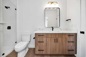 Full bath with vanity, a tile shower, and wood finished floors