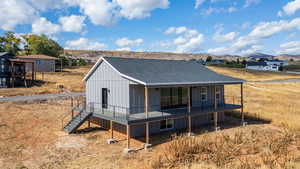 Back of house with a shingled roof, covered porch, and board and batten siding