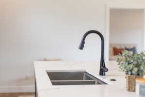 Kitchen view of light stone counters and a sink