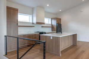 Kitchen featuring open shelves, light wood-type flooring, recessed lighting, an island with sink, and freestanding refrigerator