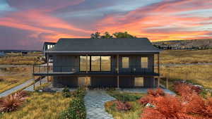 Rear view of property featuring board and batten siding, a patio area, roof with shingles, and a balcony,landscape in this photo is virtual