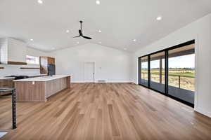 Unfurnished living room with lofted ceiling, light wood-type flooring, recessed lighting, and a ceiling fan