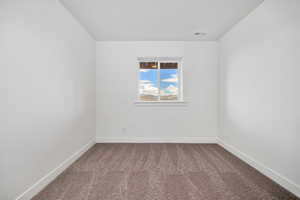 Spare room featuring dark carpet
