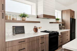 Kitchen with open shelves, black appliances, wood finish cabinets, modern cabinets, and light stone countertops